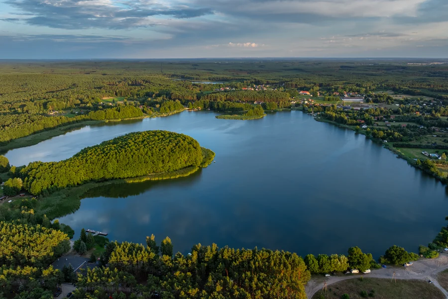 Jezioro z zalesioną wyspą otoczone lasem, widok z lotu ptaka